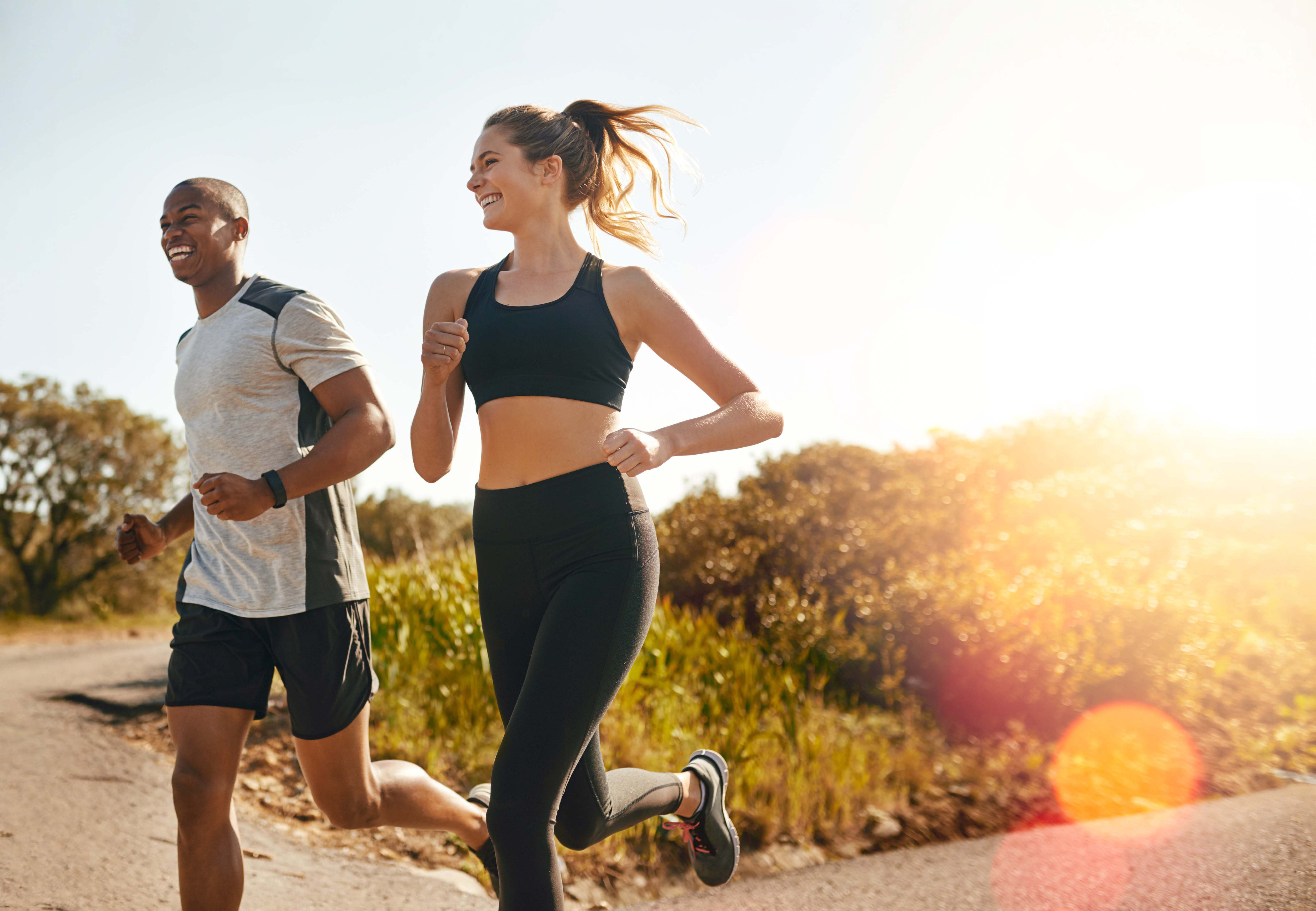 Ein Mann und eine Frau joggen im Sommer in der Natur.